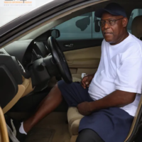 man sits in car with driver's door open