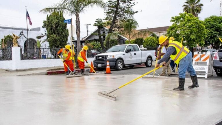 workers apply light-colored paint to city street