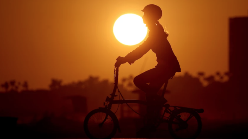silhouette of bicyclist against bright orange sun