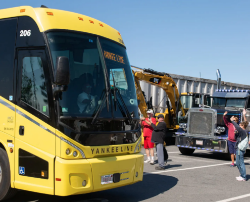 yellow bus greeted by people waving and taking pictures