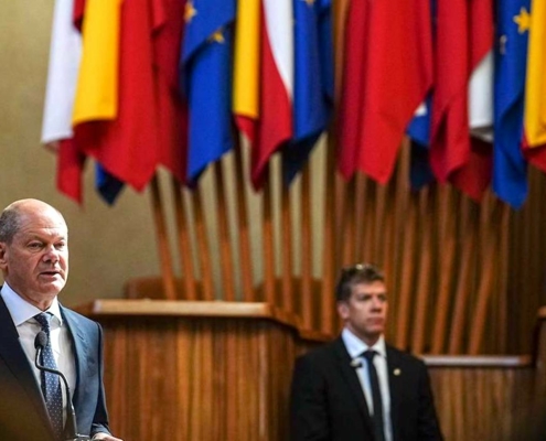 Two men in suits with flags in the background