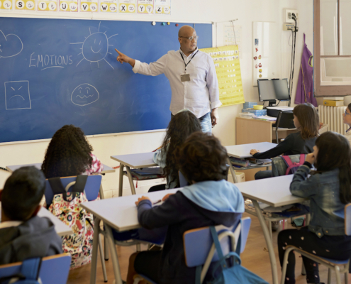 teacher at board teaching schoolchildren about emotions