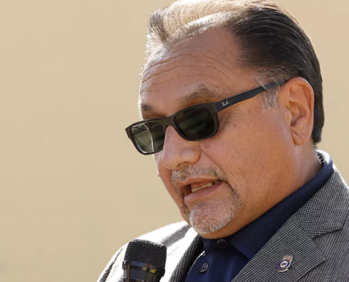 Man wearing sunglasses speaking into microphone
