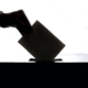 silhouette of hand placing ballot in box