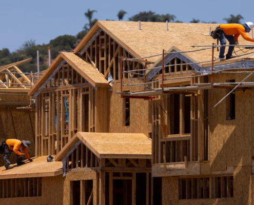 Construction worker builds the frame of a multi-story house.