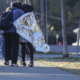 two people on sidewalk, one wrapped in metallic blanket