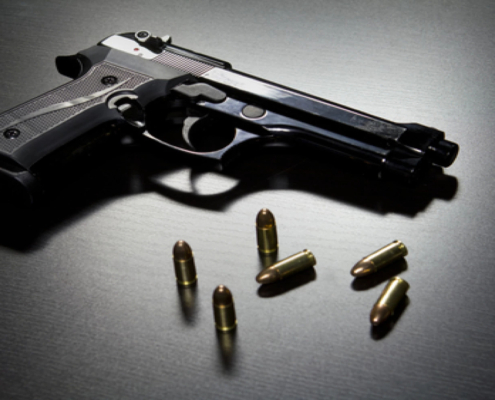 Gun on a table with bullets scattered around it.
