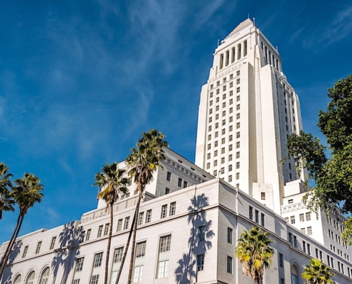white concrete building with tower with palm trees in front