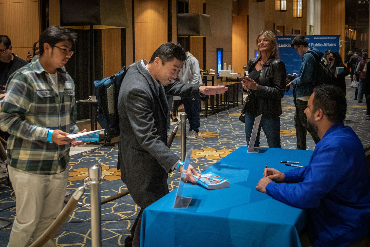 Man at desk signing books in conference center lobby