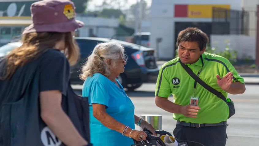 A transit ambassador assists two people by giving them directions.