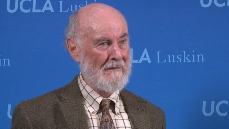 man with gray beard against blue background