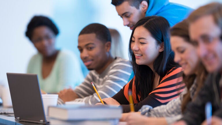 Young people at a desk with books and laptop