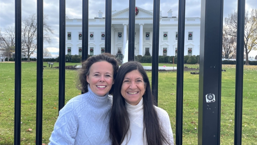 Two women in front of White House fence