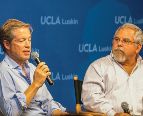 two men hold microphones as the talk