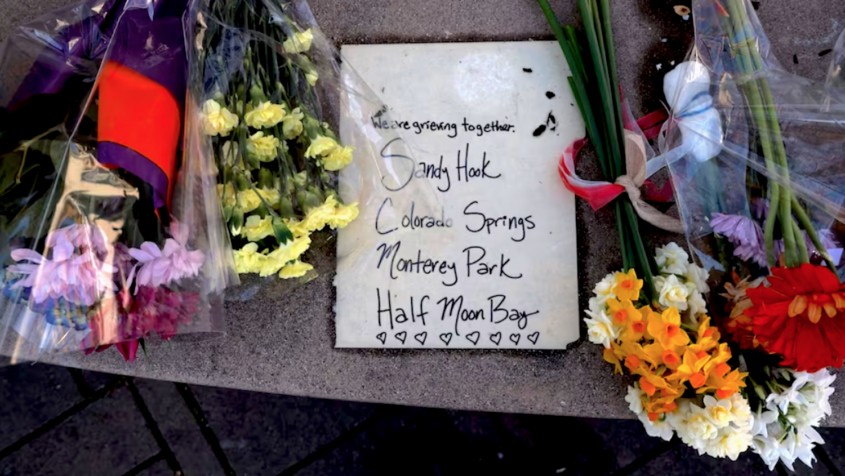 Flowers near sign of mourning for mass shootings