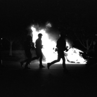 three figures silhouetted against a fire burning in the background
