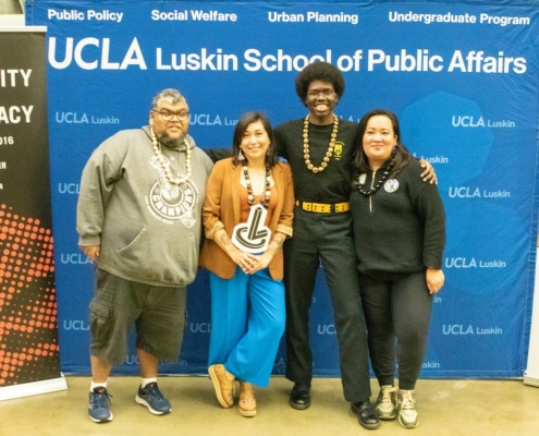 Two men and two women in front of UCLA signage