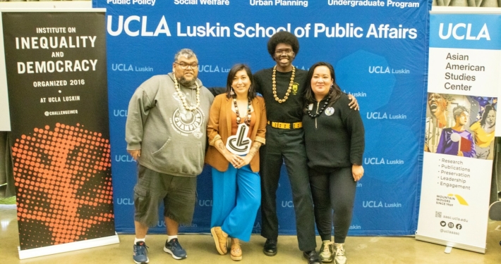 Two men and two women in front of UCLA signage