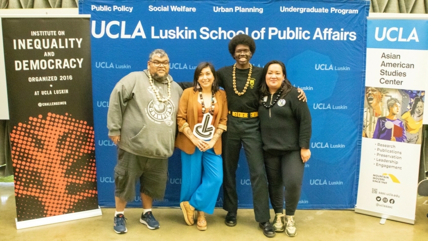 Two men and two women in front of UCLA signage
