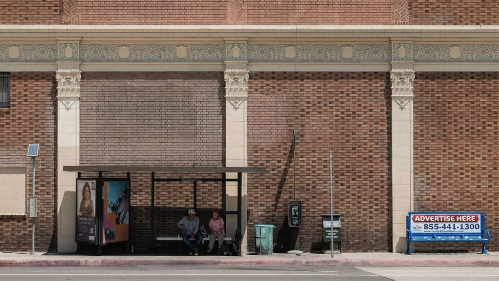 Two people sitting at bus shelter
