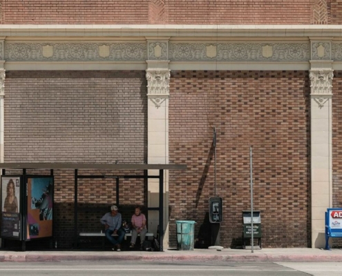 Two people sitting at bus shelter