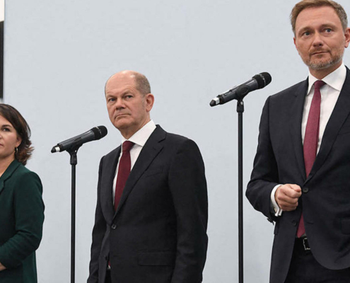 woman and two men on stage with microphones