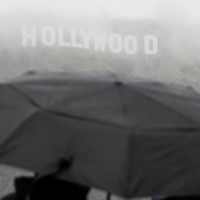 People with umbrella at Hollywood sign during storm