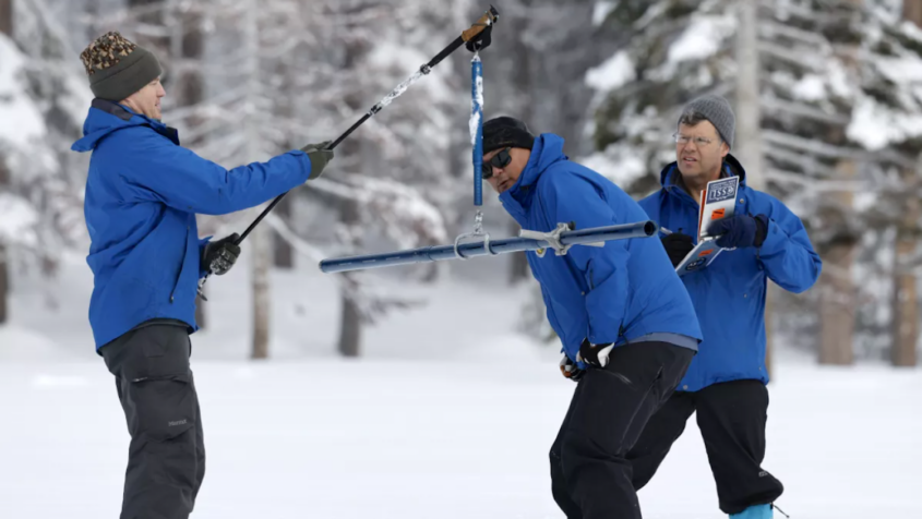 three men in blue jackets in deep snow