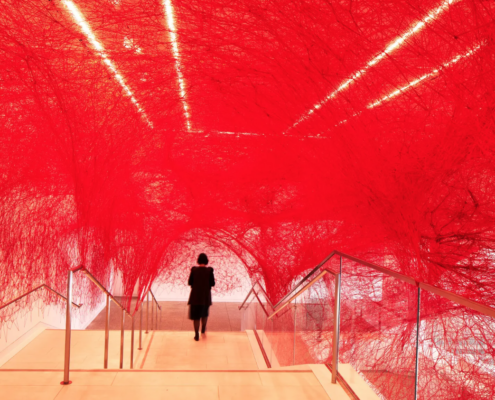 woman in museum lobby adorned with red yarn