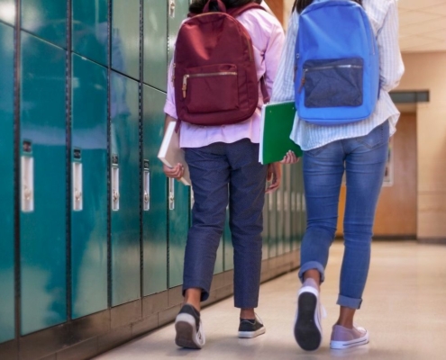 students with backpacks walking near school lockers