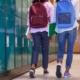 students with backpacks walking near school lockers