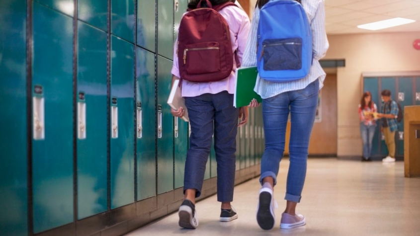 students with backpacks walking near school lockers