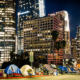 tents line a city street at night beneath skyscrapers in downtown Los Angeles