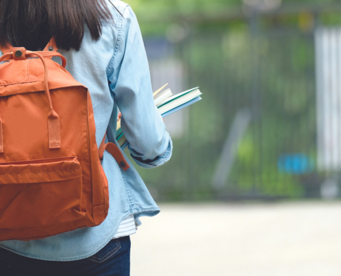 Back of student with backpack walking on street