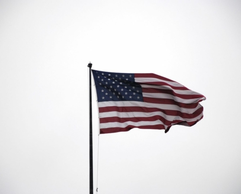 American flag waving in front of a white background.