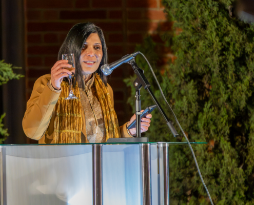 woman at podium raises champagne glass
