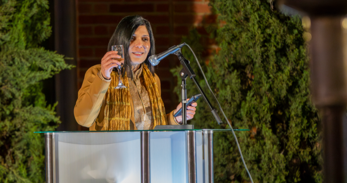 woman at podium raises champagne glass