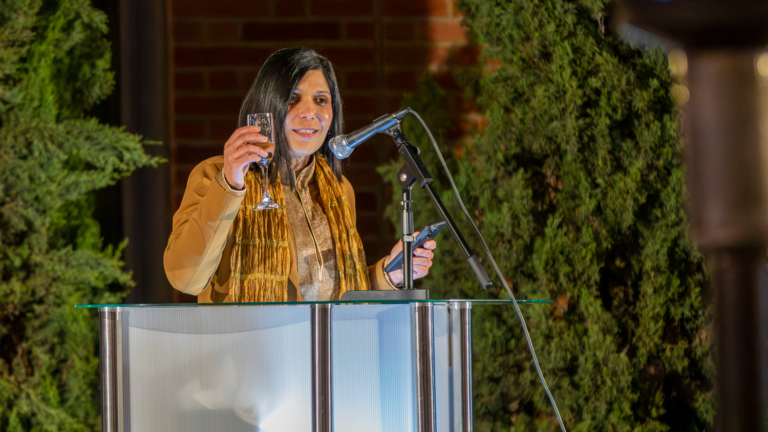 woman at podium raises champagne glass
