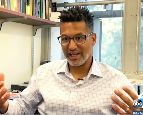 man at desk gestures while speaking