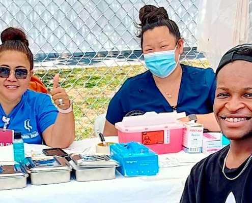 two health care workers and young man at outdoor table