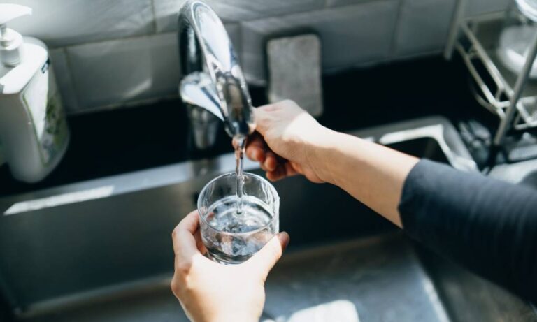 hands turn faucet to run water into a glass