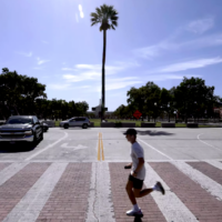 Man running in intersection with palm tree in background
