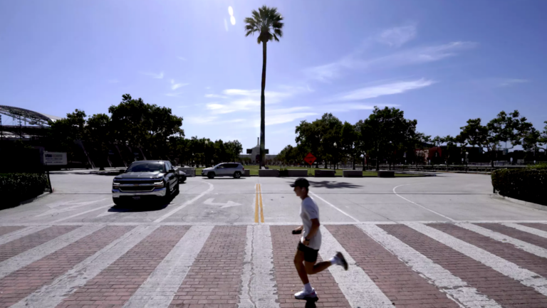 Man running in intersection with palm tree in background