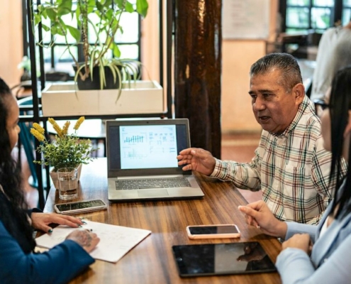 Three people at table in coffee shop with laptop open