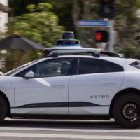 a white driverless vehicle is shown from the left side sitting on a city street