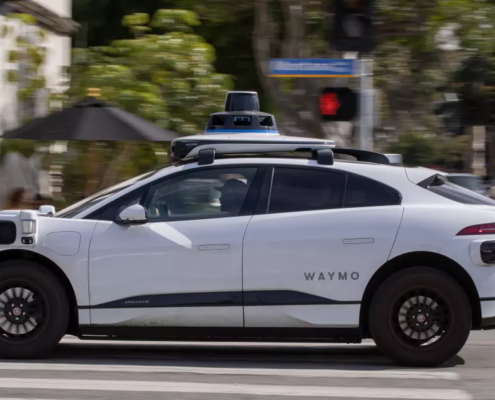 a white driverless vehicle is shown from the left side sitting on a city street