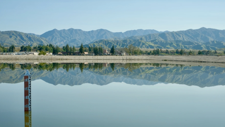 A large body of standing water is visible in the foreground, with mountains in the distance