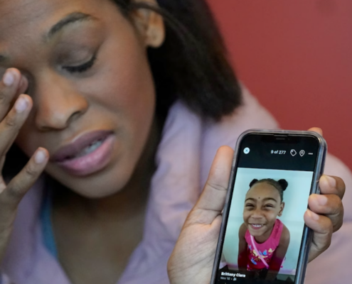 Woman holding phone showing picture of little girl