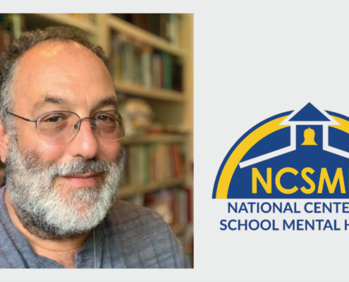 headshot of man with beard and glasses, with blue and yellow logo