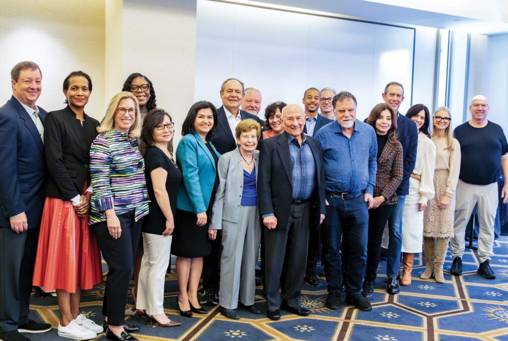 Board members gather after a meeting for a group photo|Portrait image of person in patterned white shirt|Close-up photo of person with black hair and hoop earrings|group photo of several people taken during tour of Venice Family Clinic.